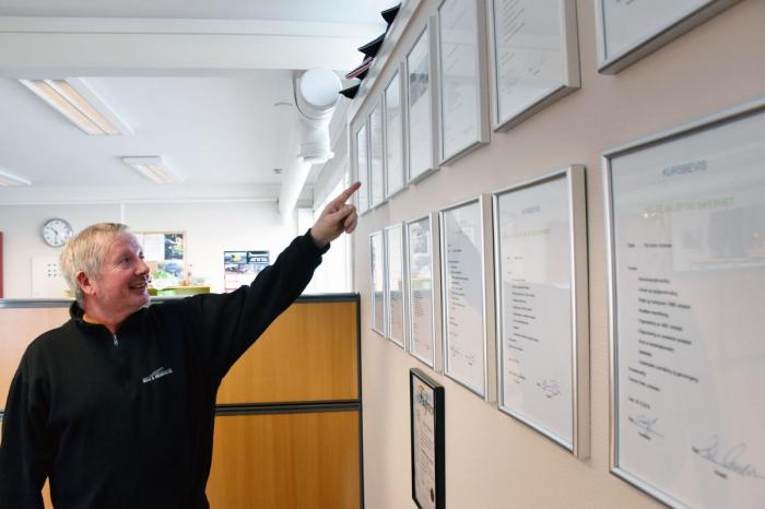 Terje Slettvold peker ut sitt HMS-bevis på veggen. Kompetanse står høyt i kurs i Kristiansen Kran & Transport. Foto: Stein Inge Stølen