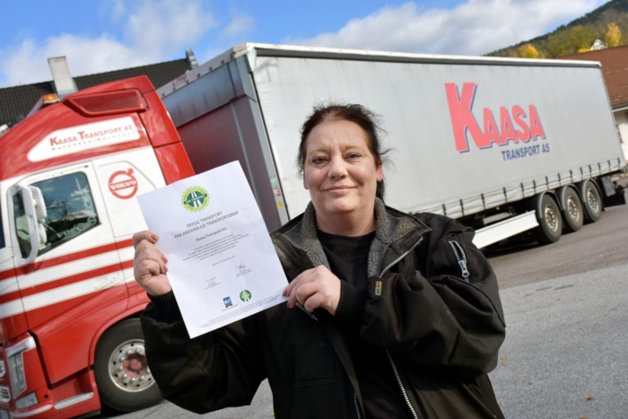 Anita viser stolt frem beviset på at Kaasa Transport nå er en Fair Transport-bedrift. Foto: Stein Inge Stølen